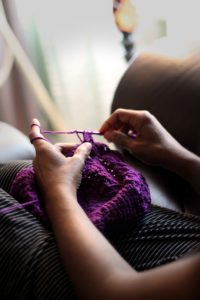 hands knitting purple yarn