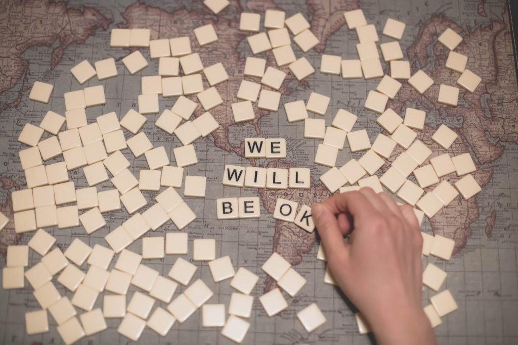 Scrabble tiles spelling out "we will be okay" on a world map