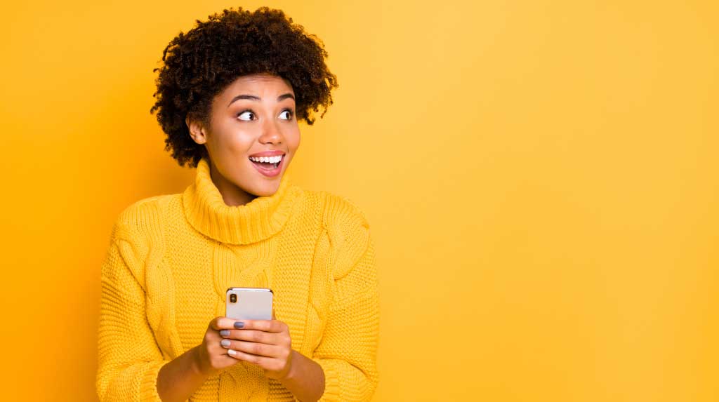 Young Black woman holding smartphone and smiling