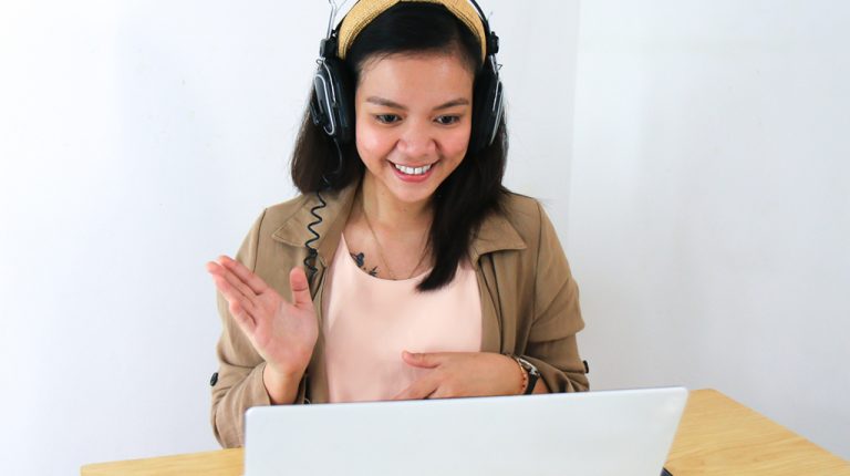 Asian woman with headphones and a laptop, smiling