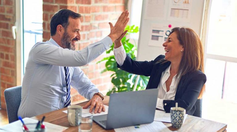 white man and woman high-fiving at business/conference table