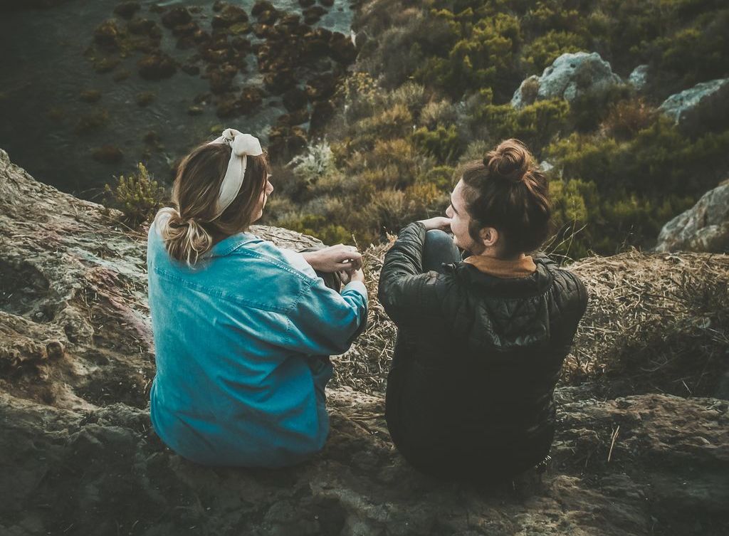 Two women talk overlooking the ocean.