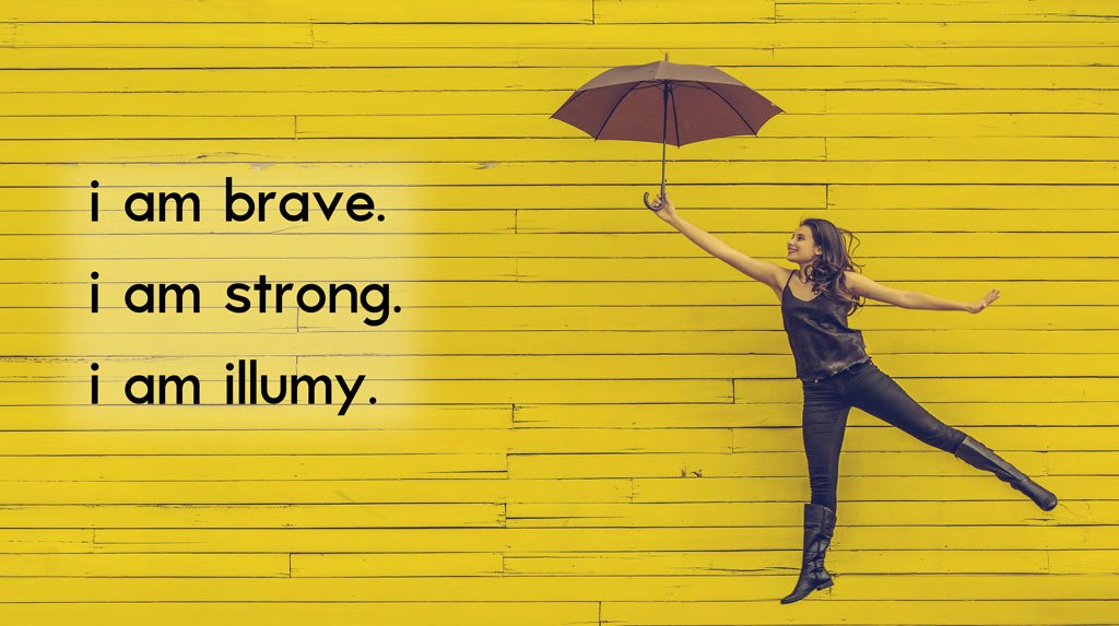 woman holding brown umbrella jumping in front of a yellow brick wall