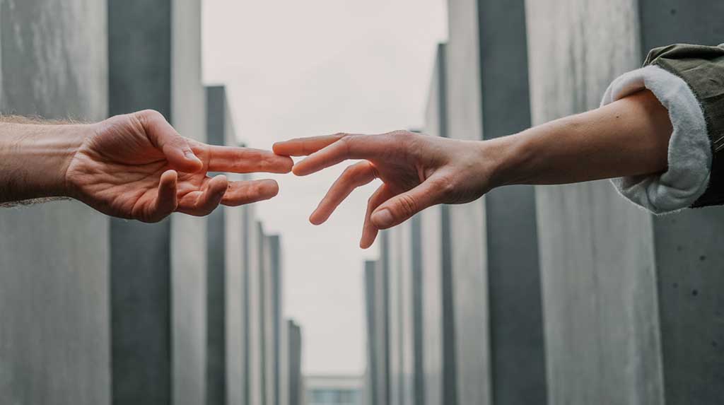 White man and woman's hands reaching out to touch