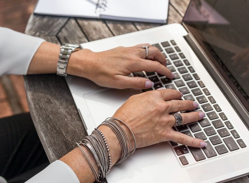 A woman's hands rest on a keyboard.