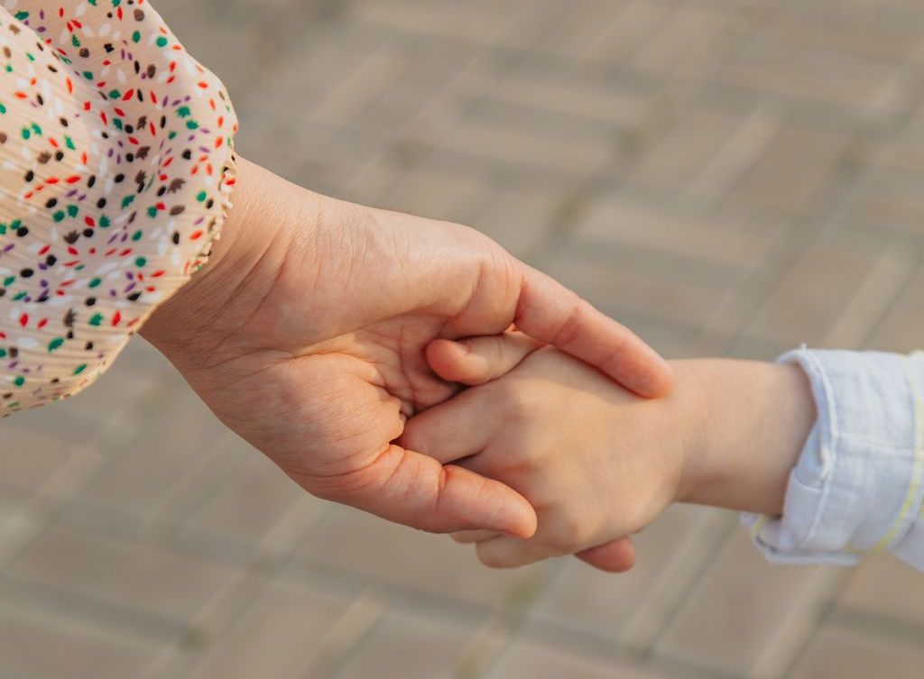 A person holds a child's hand.