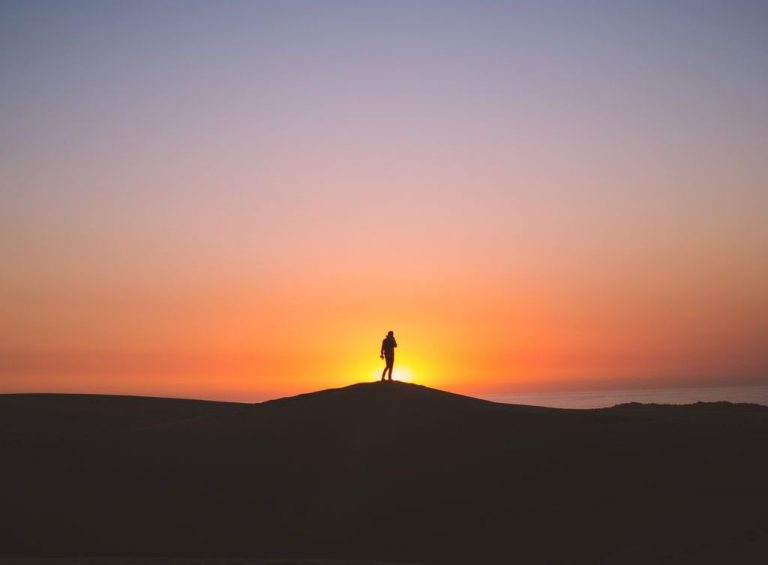 A person is silhouetted by the sunrise.