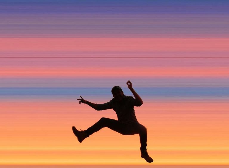 A man jumps for joy at sunset.