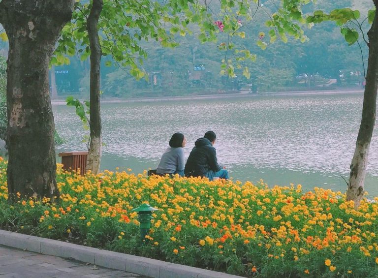 Two people sit by a river.