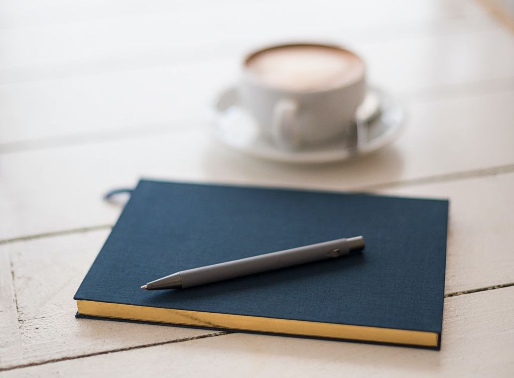 A journal and a pen sit on a desk.