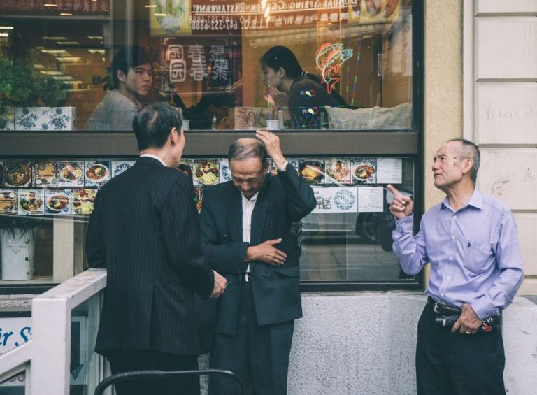 Three men converse outside a restaurant in Toronto's Chinatown.