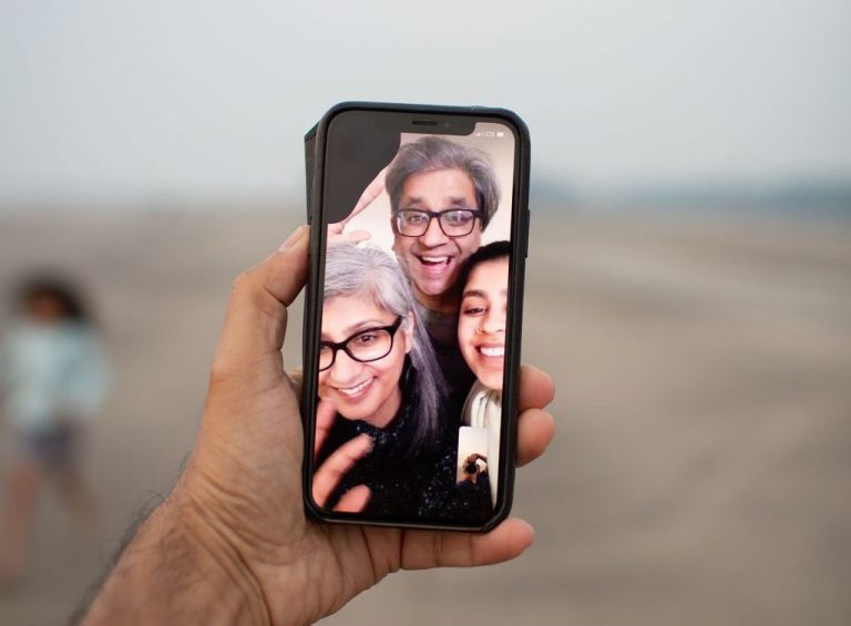 A family on a video call is captured on a smartphone screen.