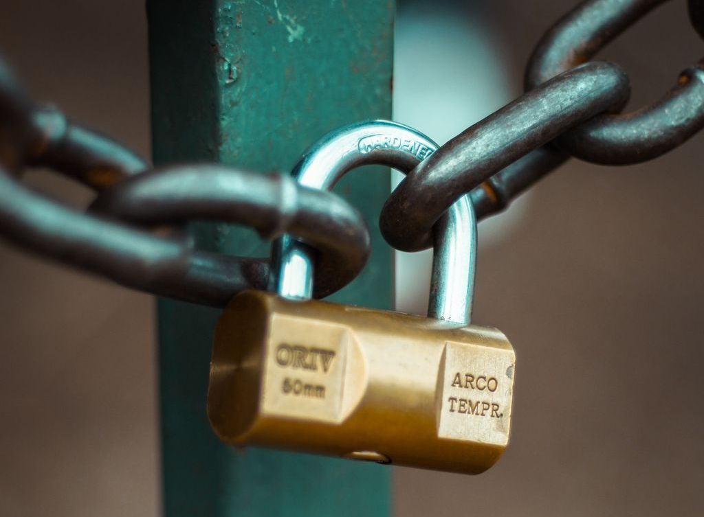 A shiny gold padlock secures a thick chain.