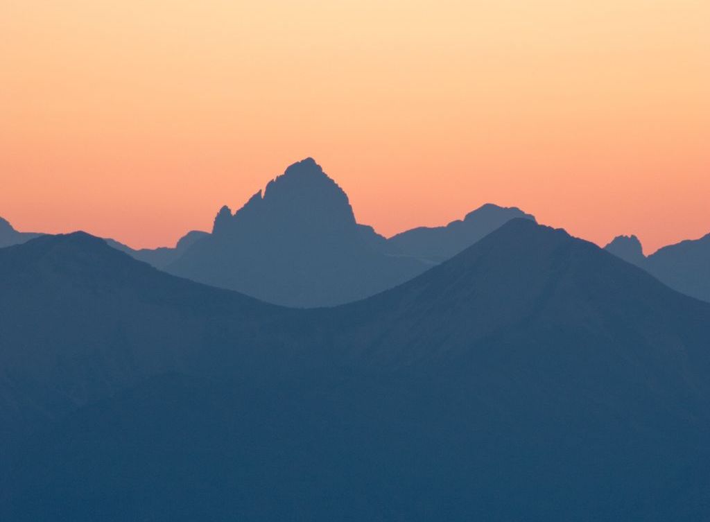 Mountains are silhouetted against the sky at sunset.