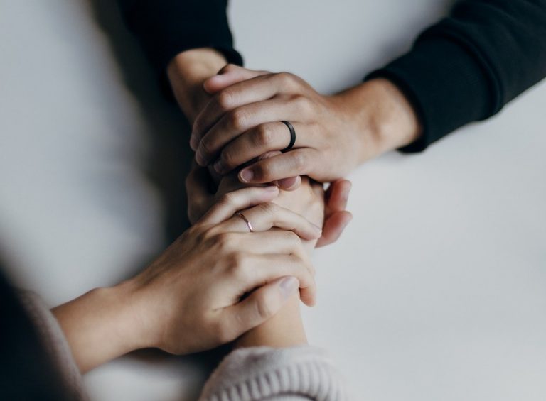 Two women hold each other's hands on a table.