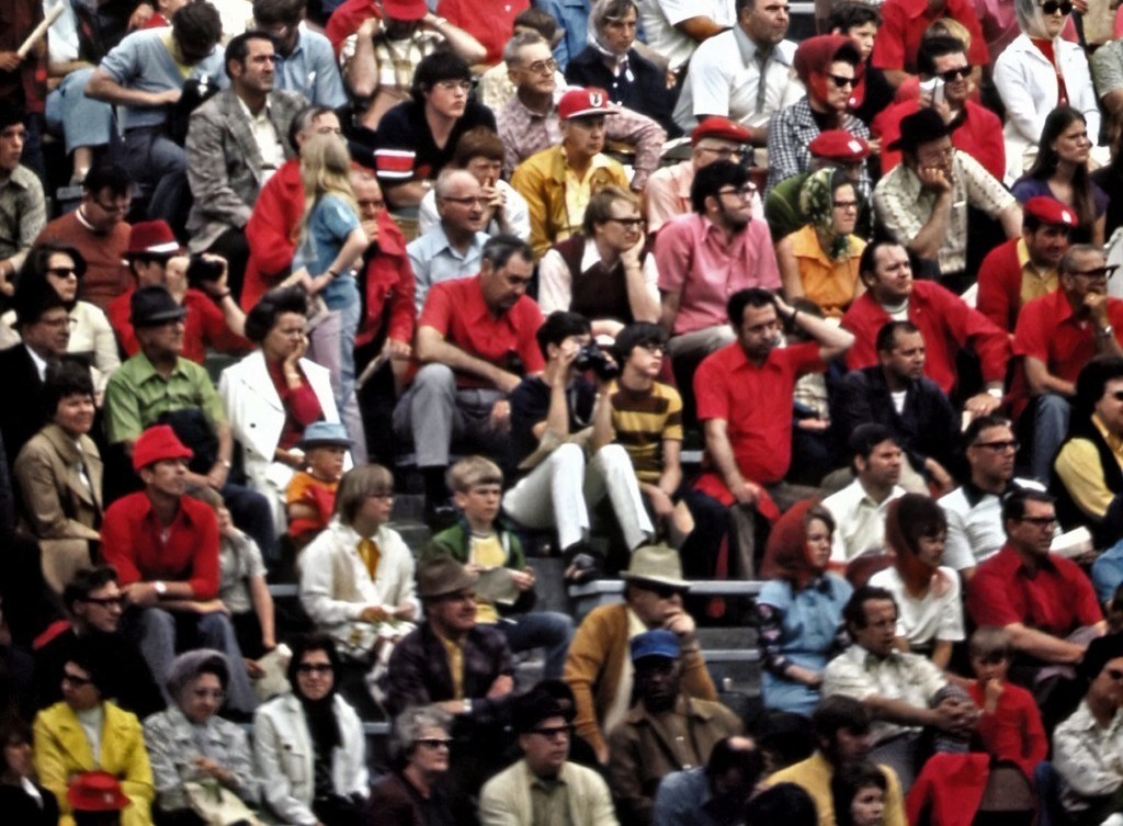 A large crowd of people watches a football game.