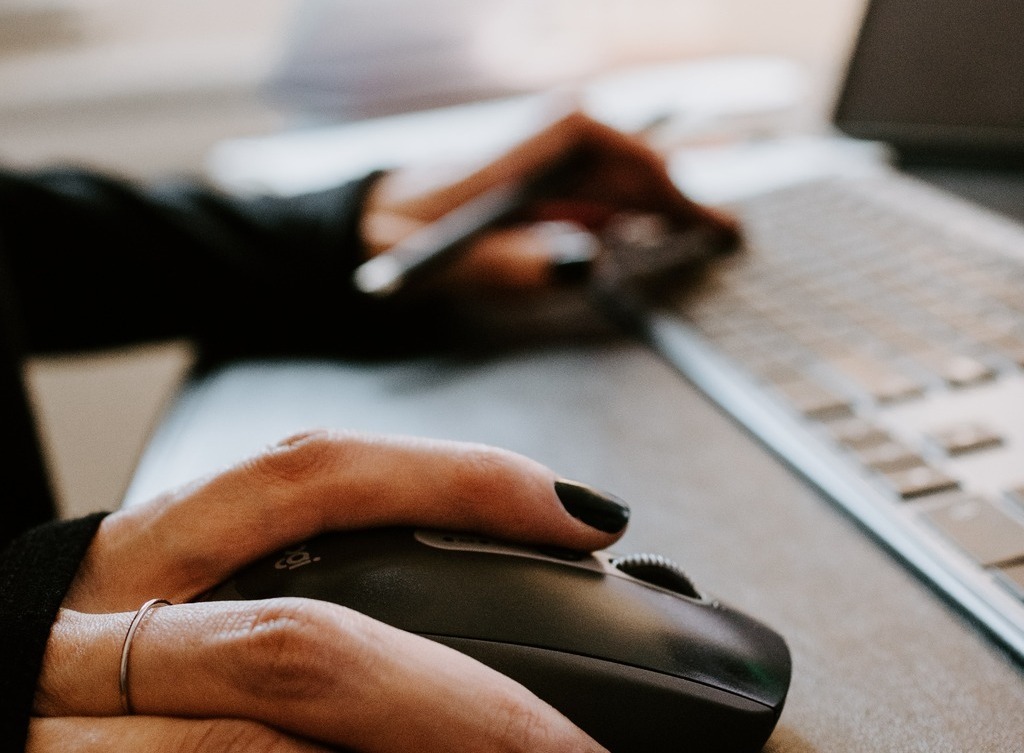 A woman's hands are shown resting on a mouse and keyboard.