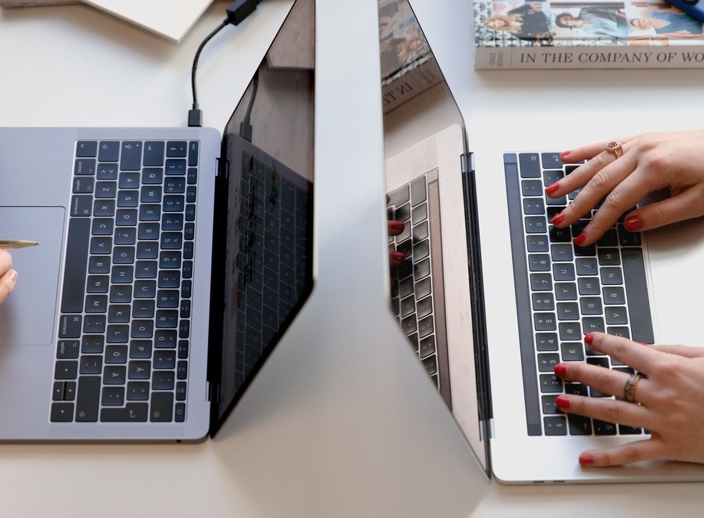 Two laptops facing each other on a desk.