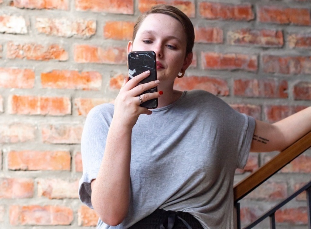 A woman smiles at her phone.