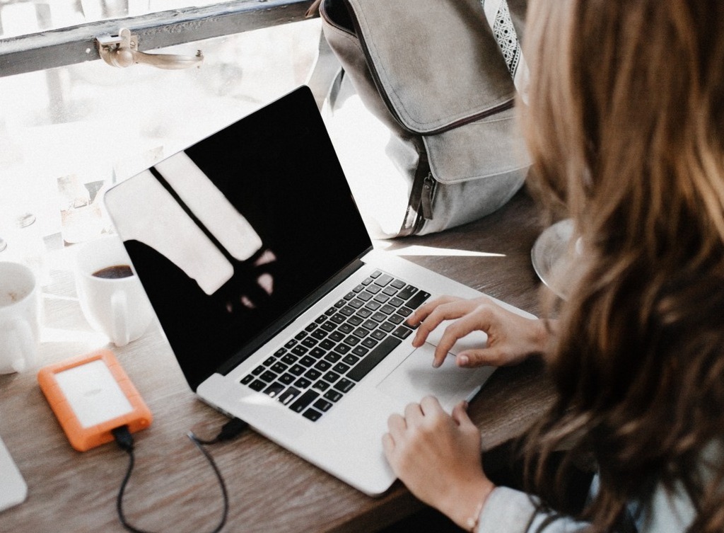 A woman types on a laptop with a dark screen.