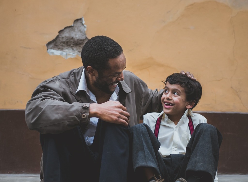 A man and a boy sit talking.