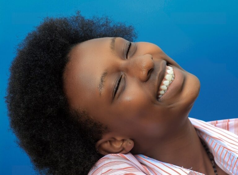 A woman smiles with her eyes closed.