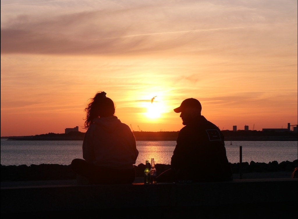 Two people engage in conversation at sunset.