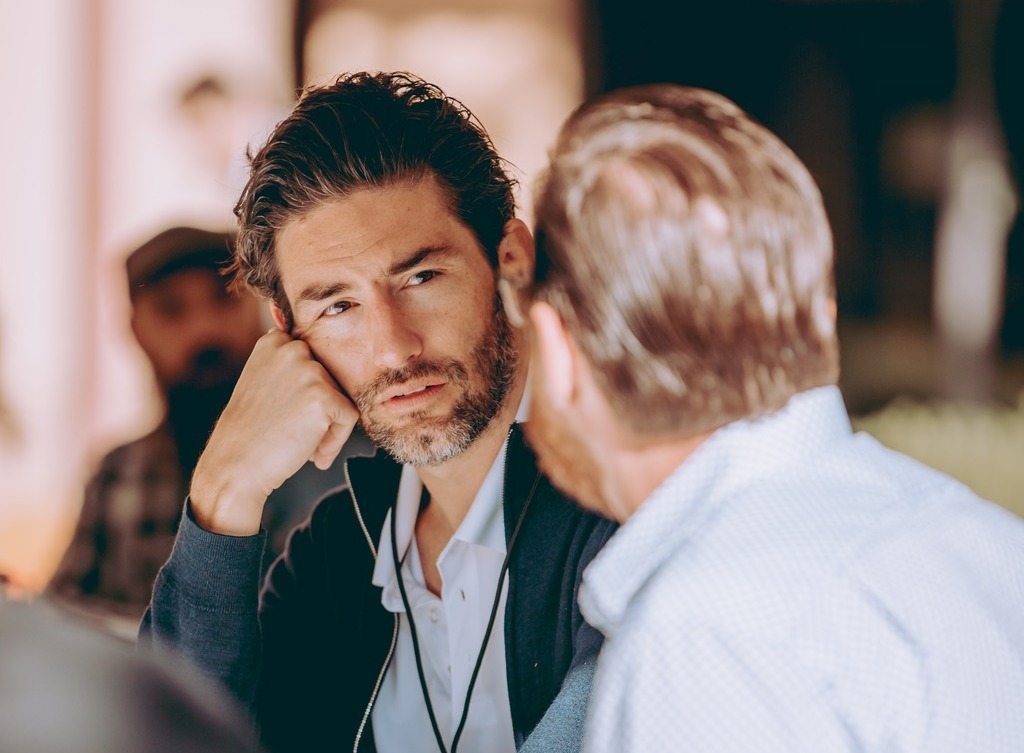 Two men talk at a bar.